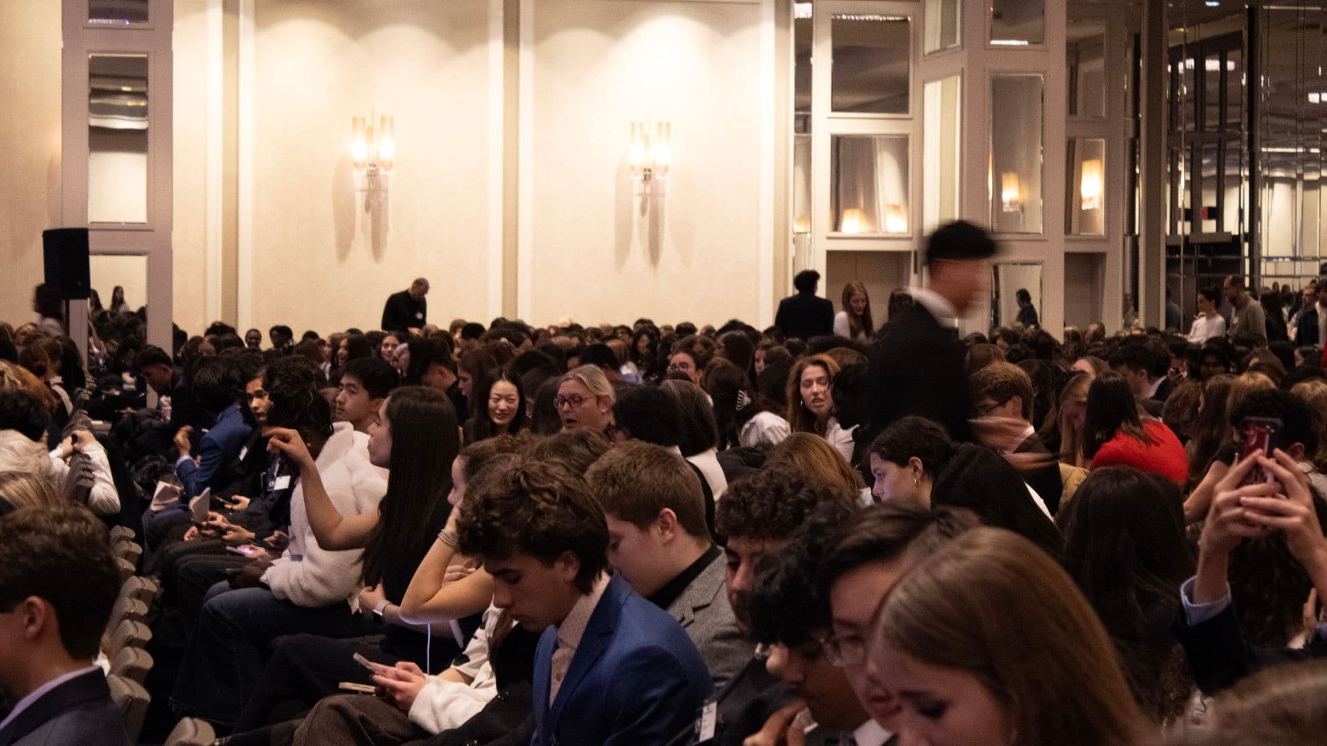 Delegates entering plenary hall under blue conference lighting